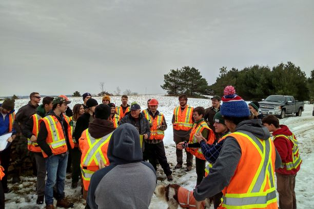 Large group of students stand around Ralph as he speaks