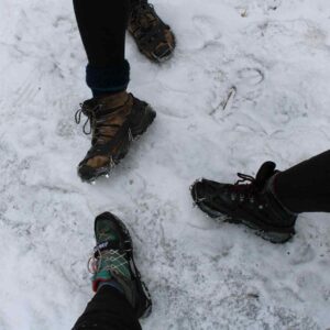 Three people displaying their hiking boots and ice cleats