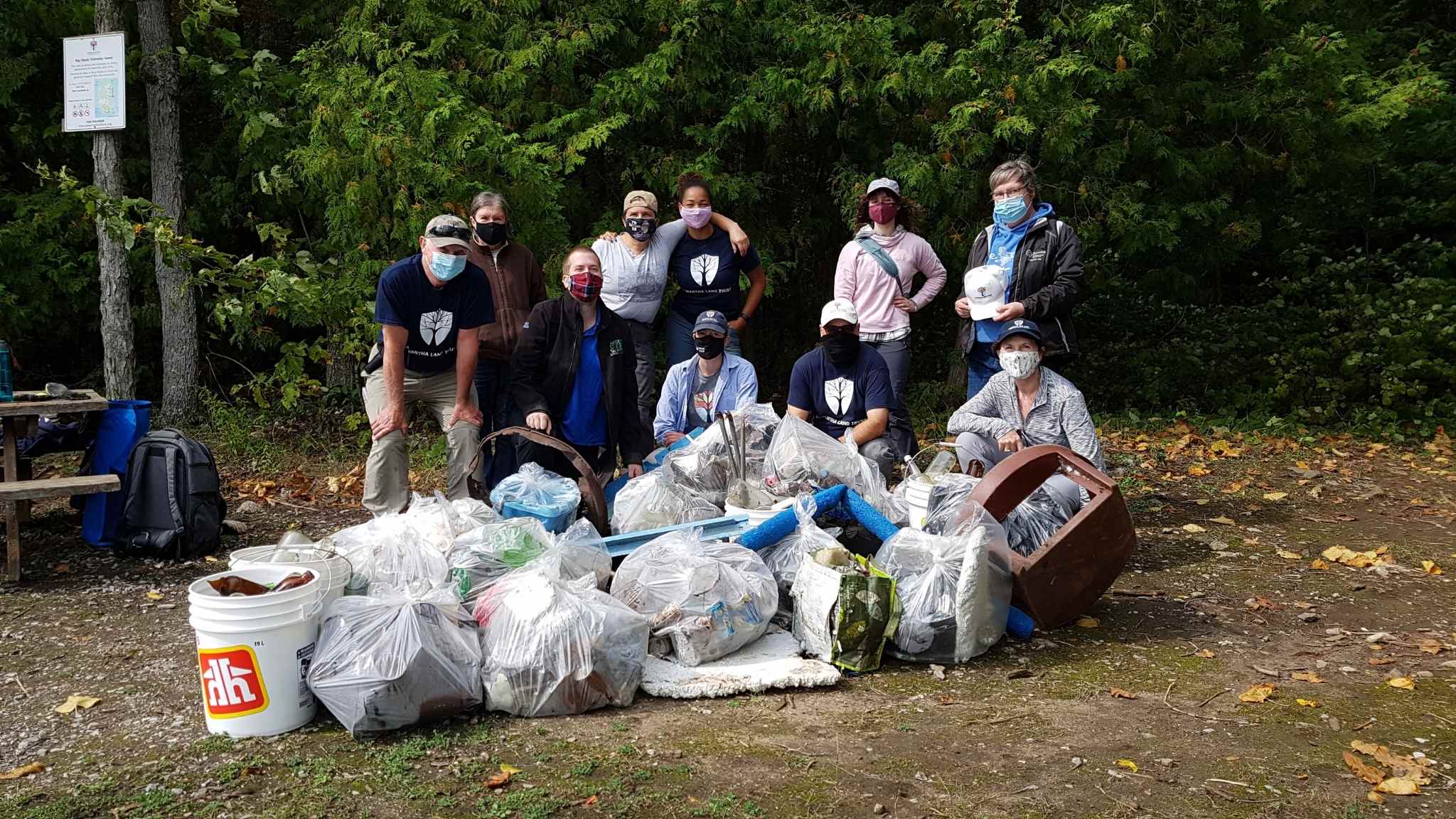 Volunteers and staff group shot beside the garbage they cleaned up from the shoreline