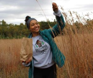 Patricia Wilson, wearing a Diverse Nature Collective sweatshirt, collecting tallgrass seeds at Ballyduff Trails