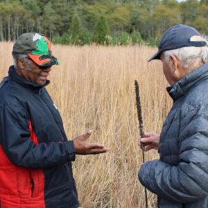 Two people discussing tallgrass prairie plant species at ballyduff Trails in fall