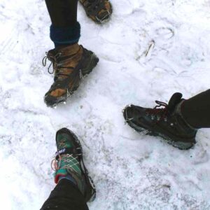 Three hikers showing off their ice crampons