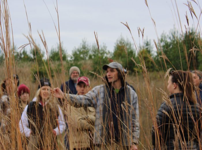 Hayden Wildson Kawartha Land Trust Stewardship Manager showing volunteers how to collect tallgrass seeds